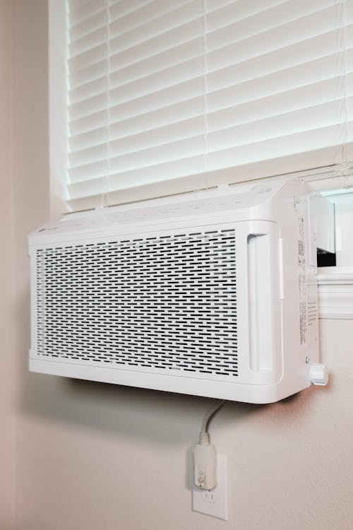 A white air conditioner below a window inside a house