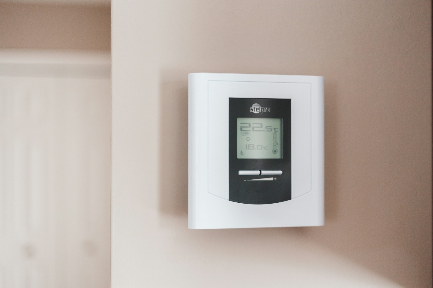 A white thermostat with a reading of 22.5 degrees Celsius on a wall