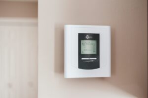 An image of a white and black thermostat with a reading of 22 degrees Celsius, mounted on a wall